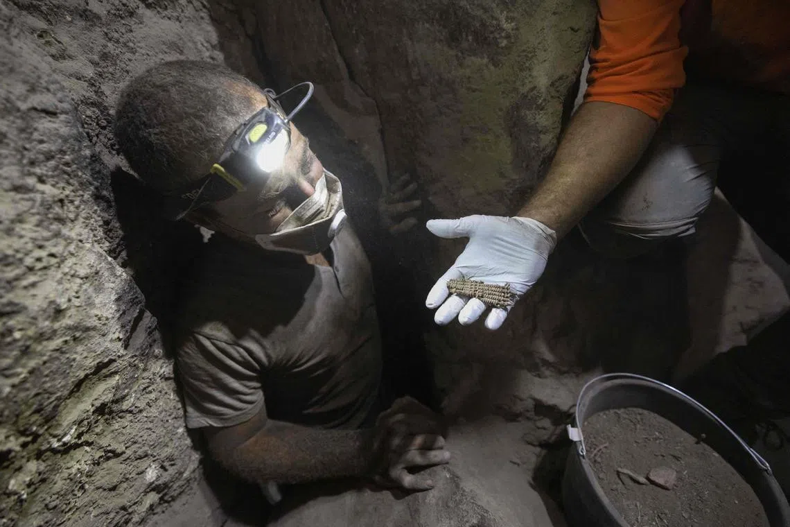 A member of the Israel Antiquities Authority (IAA) team displays a find unearthed at an excavation site in the Murabaat cave in the Judean Desert area near the Dead Sea, on December 28, 2022. 