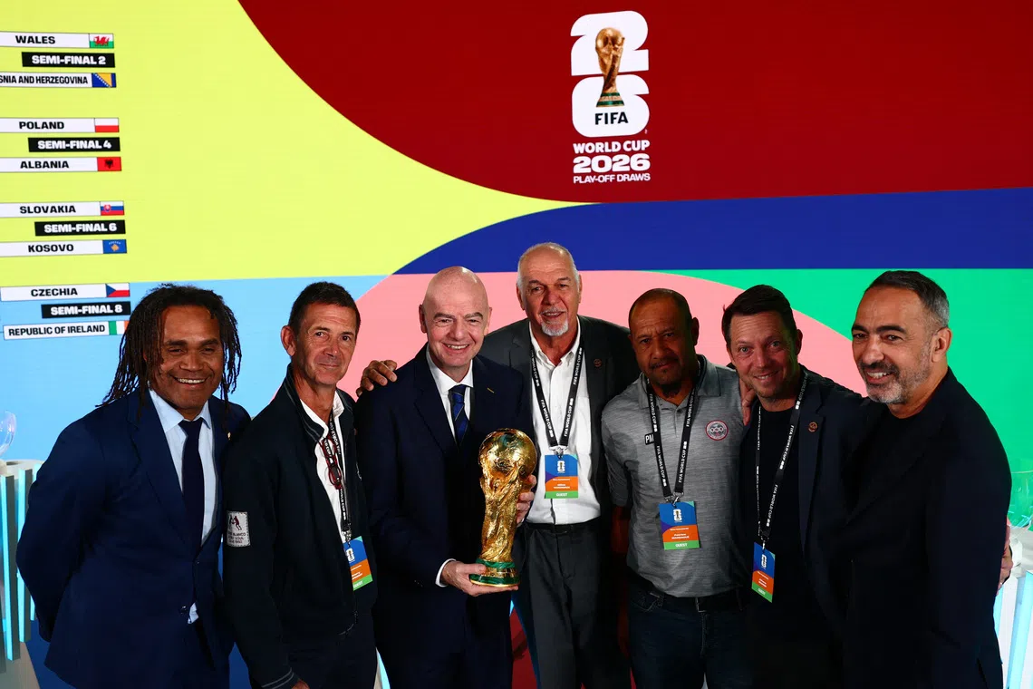 Soccer Football - World Cup Playoff Tournament and European Playoff draws - FIFA Headquarters, Zurich, Switzerland- November 20, 2025 FIFA president Gianni Infantino holds the World Cup trophy and poses for a photograph with New Caledonia football federation president Gilles Tavergeux, staff members and former France player and 1998 FIFA World Cup winner Christian Karembeu after the draw REUTERS/Denis Balibouse