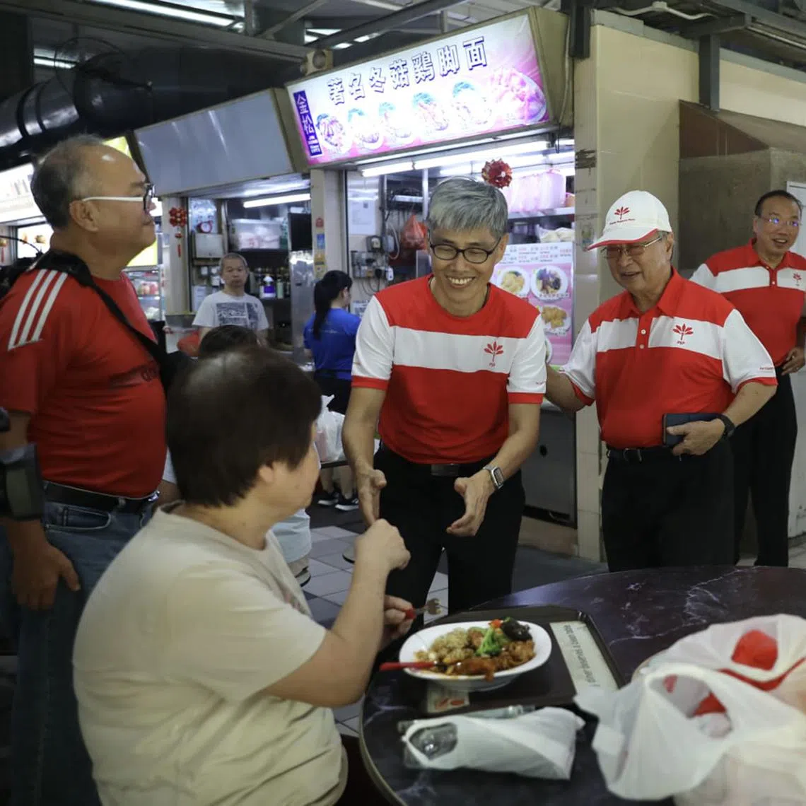 PSP's Kebun Baru candidate Tony Tan (left) and party chairman Tan Cheng Bock greeting residents during a walkabout at Mayflower Market and Food Centre on April 27.