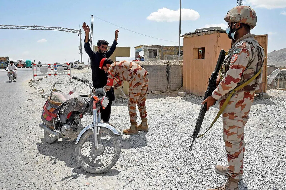 TOPSHOT - A Pakistani paramilitary ranger frisks a motorcyclist at a checkpoint a day after attacks by separatist militants on the outskirts of Quetta on August 27, 2024. Pakistani forces hunted separatist militants on August 27, who killed dozens when they pulled passengers off buses, blew up a bridge and stormed a hotel a day earlier. (Photo by Banaras KHAN / AFP)