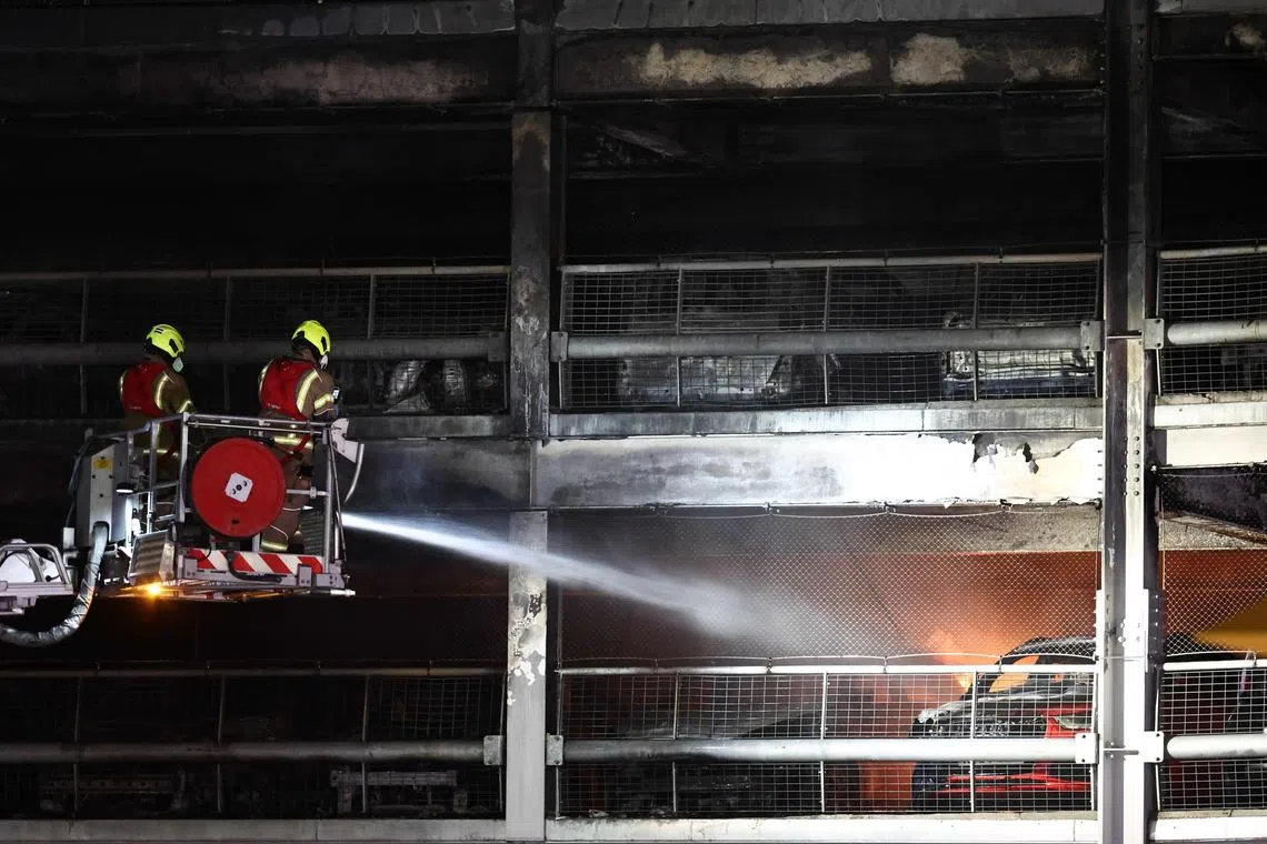 Firemen battle a fire at London's Luton Airport which caused a partial collapse of a parking structure in Luton on October 11, 2023. Five people, including four firefighters and an airport employee, were admitted to hospital, according to the local ambulance service. (Photo by HENRY NICHOLLS / AFP)