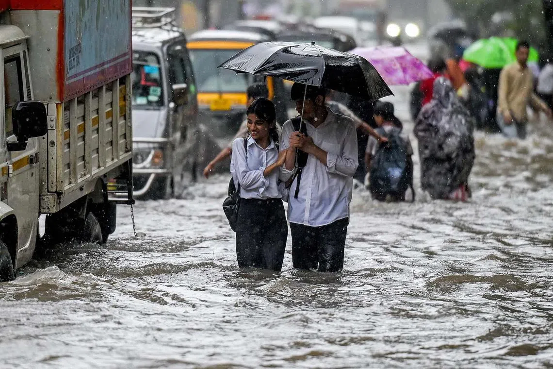 People wading through a flooded street during heavy rain showers in Mumbai, India, on Aug 18, 2025. 