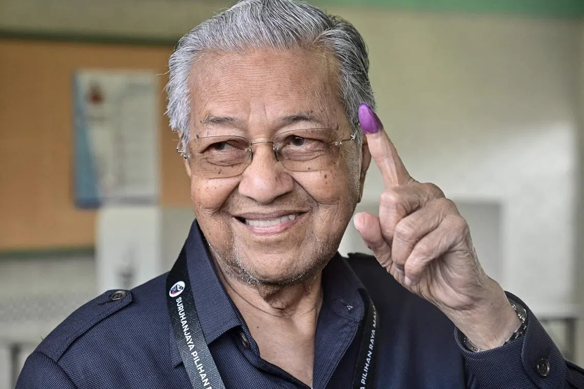 This handout photo taken on November 19, 2022 and released on November 20 by Malaysia's Department of Information shows former Malaysia prime minister Mahathir Mohamad showing his inked finger after casting his vote at a polling station during the general election in Kuala Kedah district, Malaysia's Kedah state. 