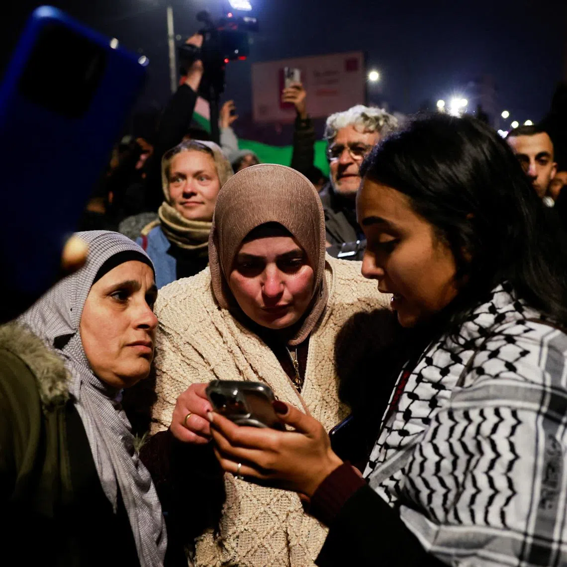 Women look at a mobile phone screen in Ramallah, in the Israeli-occupied West Bank, January 20, 2025. REUTERS/Ammar Awad/File Photo