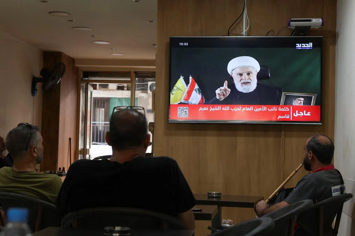 People watch Hezbollah deputy leader Sheikh Naim Qassem delivering a televised address, as they sit in a cafe in Beirut, Lebanon October 15, 2024. REUTERS/Mohamed Azakir
