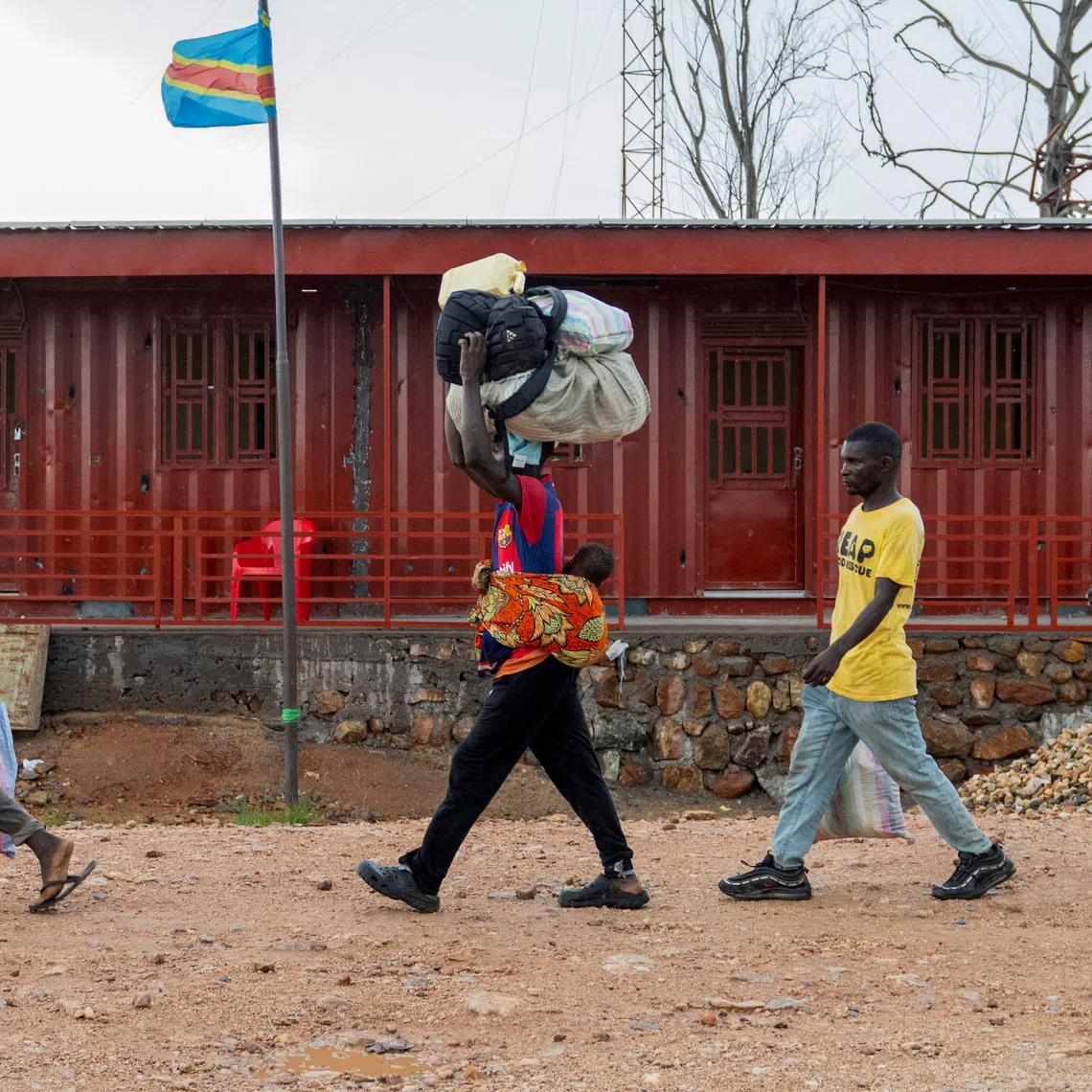 Foreigners who had been stranded during clashes between members of the Alliance Fleuve Congo AFC-M23 Movement who took over Uvira town from the Armed Forces of the Democratic Republic of the Congo (FARDC), walk to cross the border point in Uvira, on the shores of Lake Tanganyika, in South Kivu province, in the Democratic Republic of Congo December 14, 2025. REUTERS/Stringer