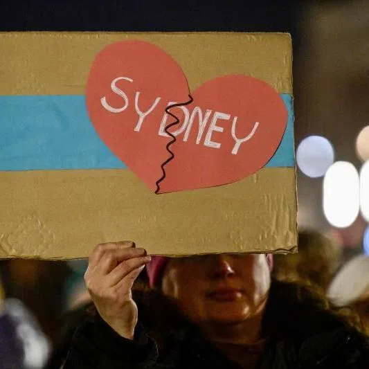 A woman taking part in a Chanukka festival in Berlin holds up a placard with a heart and the inscription "Sydney" on Dec 14.