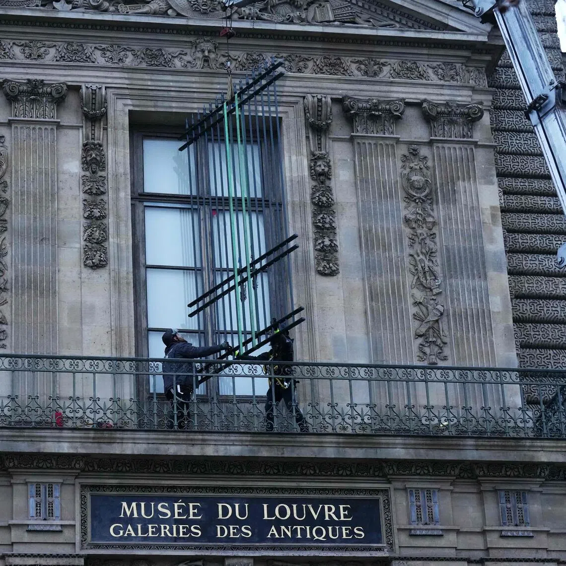 Workers install metal bars on a window at the Louvre Museum that thieves broke into on Oct 19, 2025.

