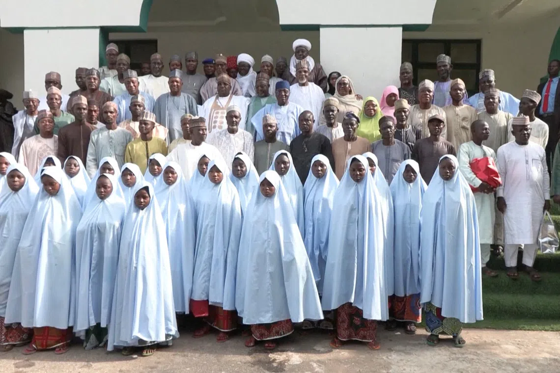 Released schoolgirls wearing blue hijabs pose for photos with their parents and government officals after the girls were freed from captivity in northwestern Nigeria, in Kebbi, Nigeria, November 26, 2025, in this screengrab from video. Reuters TV via REUTERS