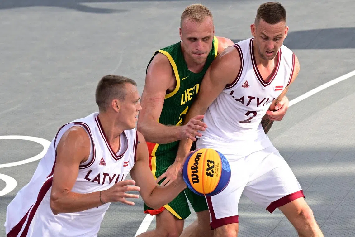 Paris 2024 Olympics - Basketball 3x3 - Men's Pool Round - Latvia vs Lithuania - La Concorde 1, Paris, France - July 30, 2024. Nauris Miezis of Latvia and Karlis Lasmanis of Latvia in action against Evaldas Dziaugys of Lithuania. REUTERS/Angelika Warmuth