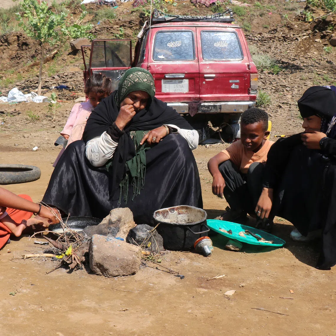 A displaced woman, Nabiha Salem, eats with her children at a makeshift camp for people displaced by clashes between Iran-aligned Houthi fighters and Saudi-backed Yemeni government forces, in Taiz province, Yemen September 21, 2026. REUTERS/Stringer