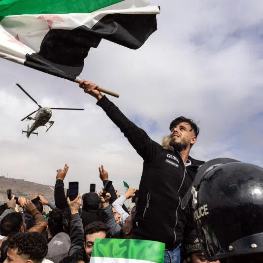 Syrians gather for a military parade in Damascus, on Dec 8.