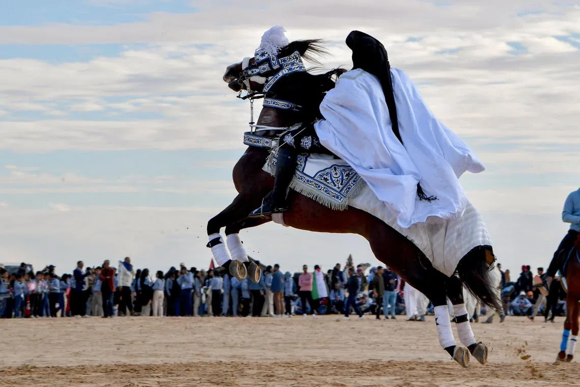 A performer wearing traditional outfit riding a horse at the start of the International Sahara Festival on Dec 27, 2023 in Douz, in southern Tunisia. 