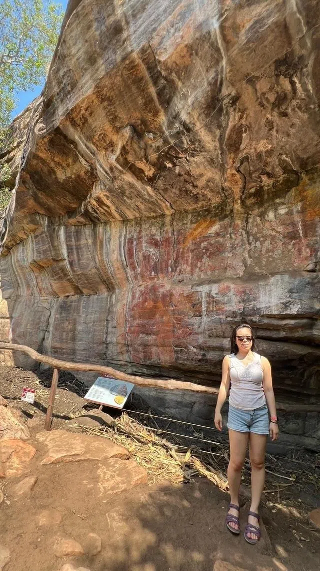 Asian woman standing in front of ancient rock art at Kakadu National Park.