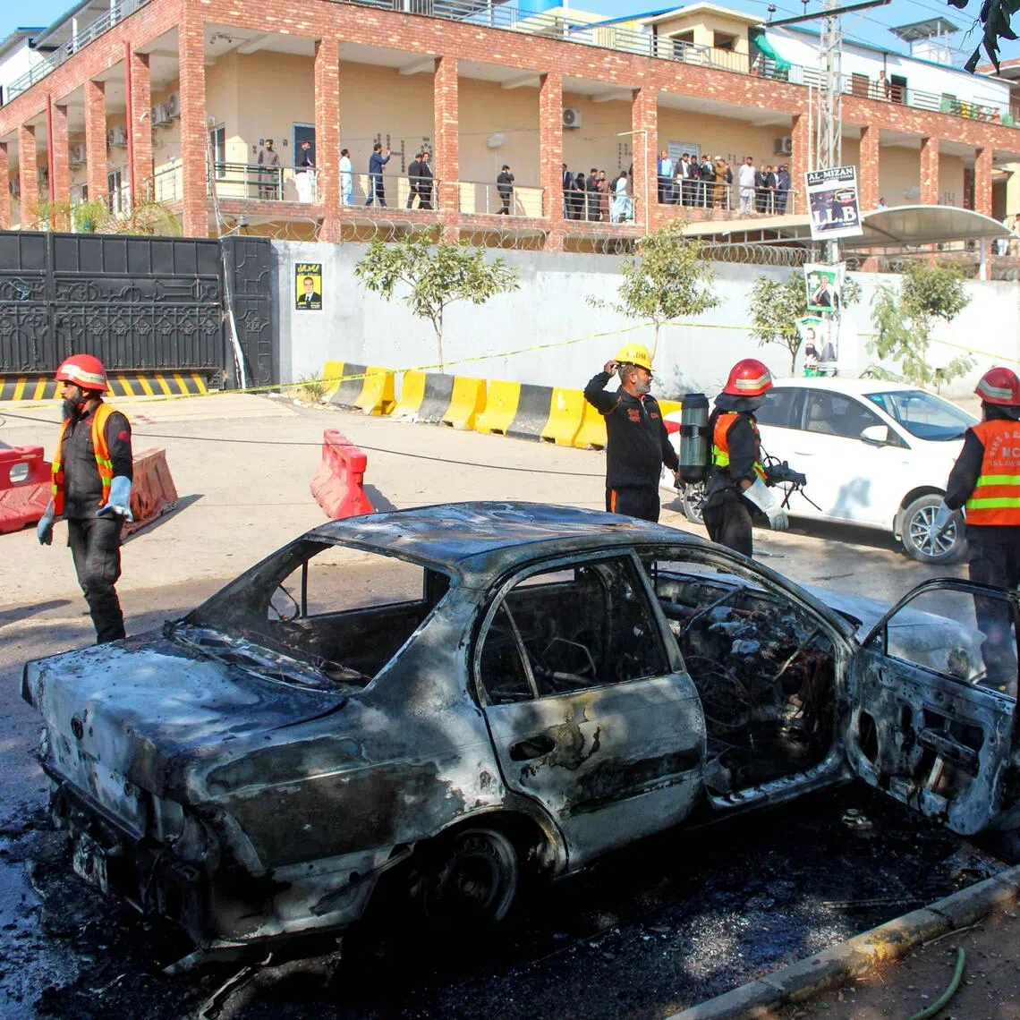 Firefighters douse a car at the suicide blast site in Islamabad on Nov 11.