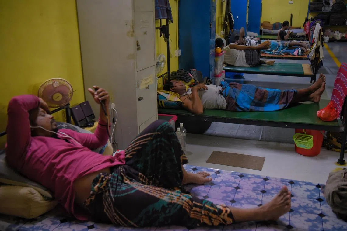 Migrant workers resting in their room in a dormitory in Tech Park Crescent after returning from work. 