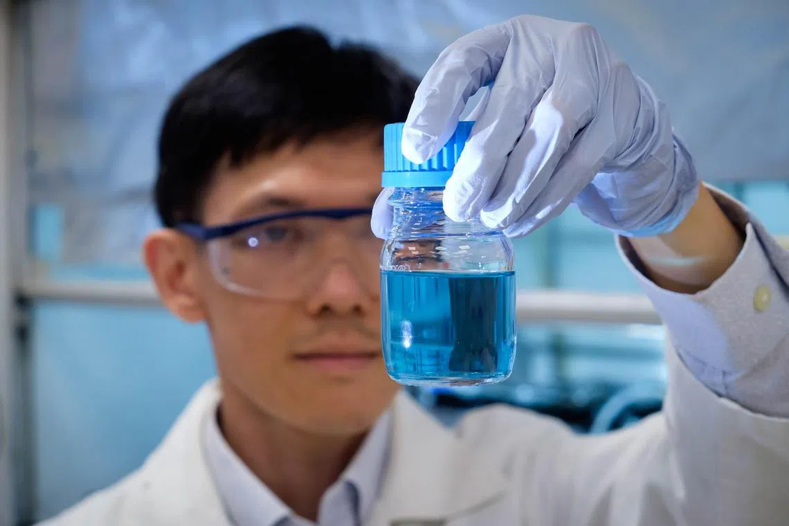 lhplastic17 - Assoc Prof Soo Han Sen looking at a bottle of solution with dissolved plastic and vanadium catalyst.

Credit: NTU Singapore