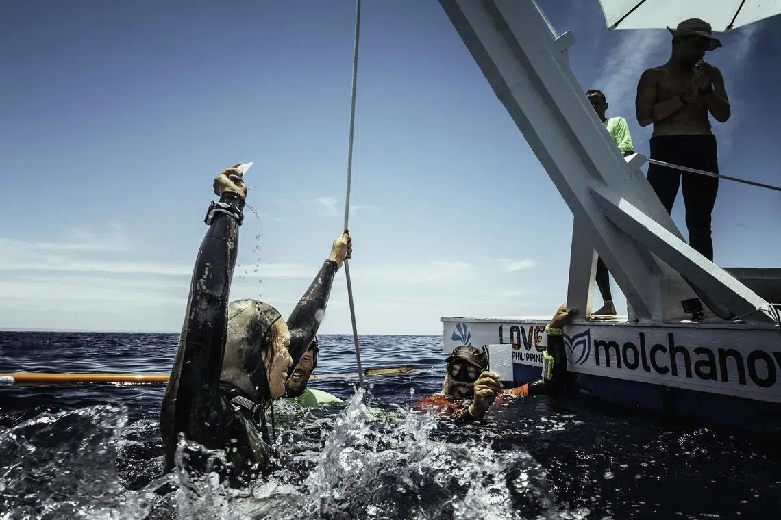 Patricia Ong, 34, raises the white tag which she retrieved from her target after completing her dive.