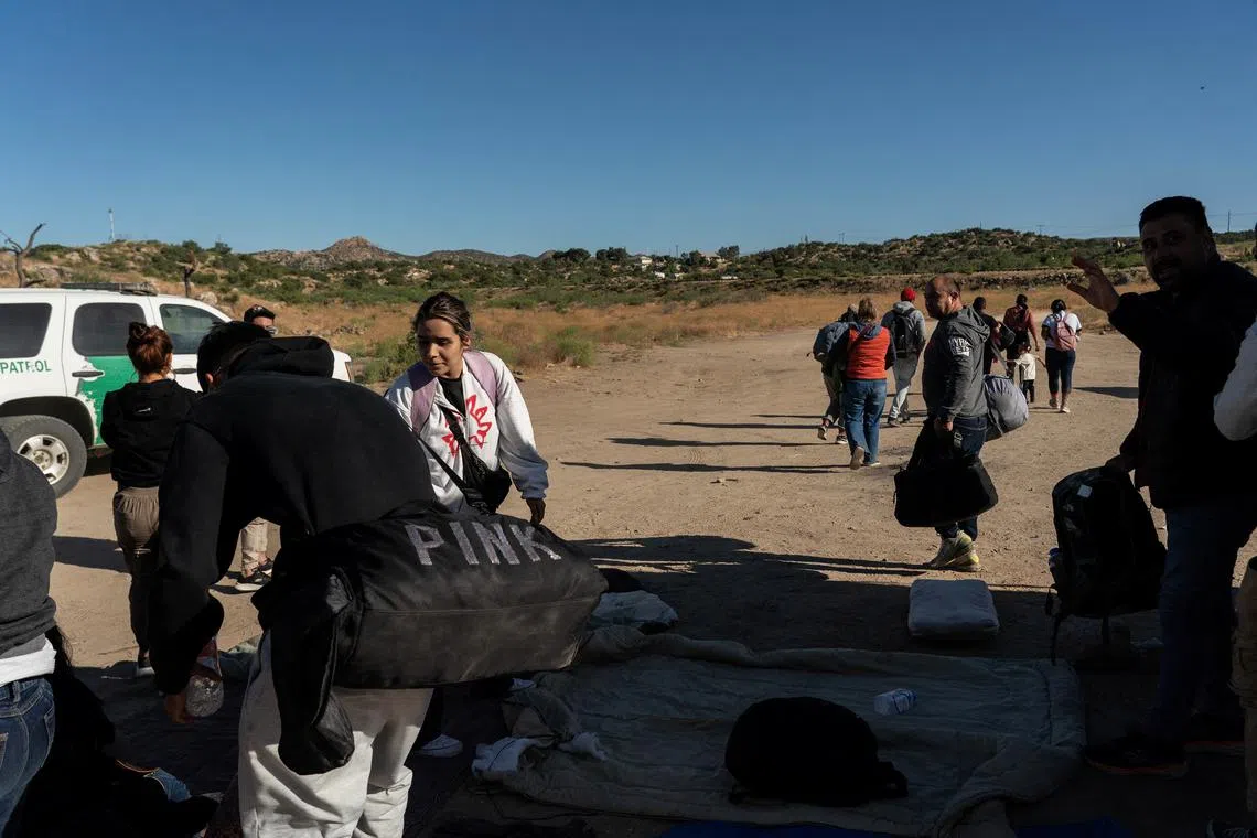 Asylum-seeking migrants from Colombia and the Dominican Republic gather their belongings to move towards the main road to be transported on June 7, as others walk towards the road, after U.S. President Joe Biden announced a sweeping border security enforcement effort, in Jacumba Hot Springs, California.