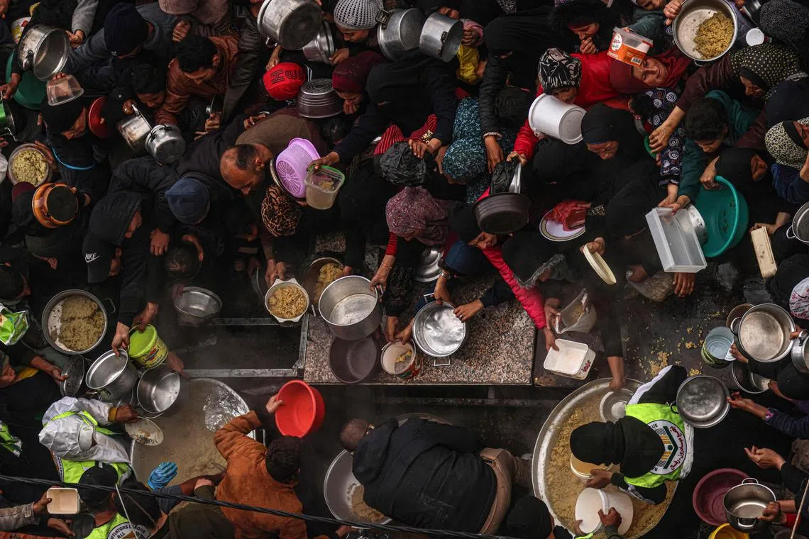Palestinians receive food rations at a donation point at a camp for internally displaced people in Rafah in the southern Gaza Strip.