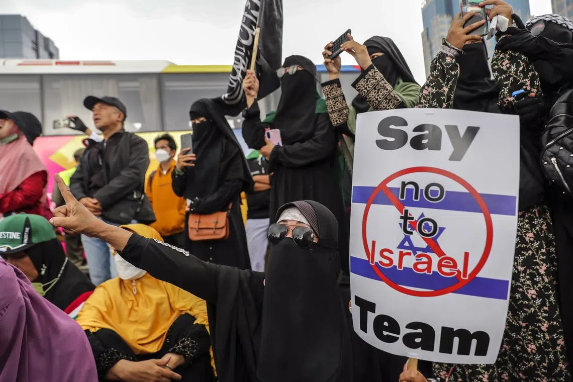 A protester shouts slogans as she holds a placard during a rally against Israel in Jakarta, on March 20, 2023. 