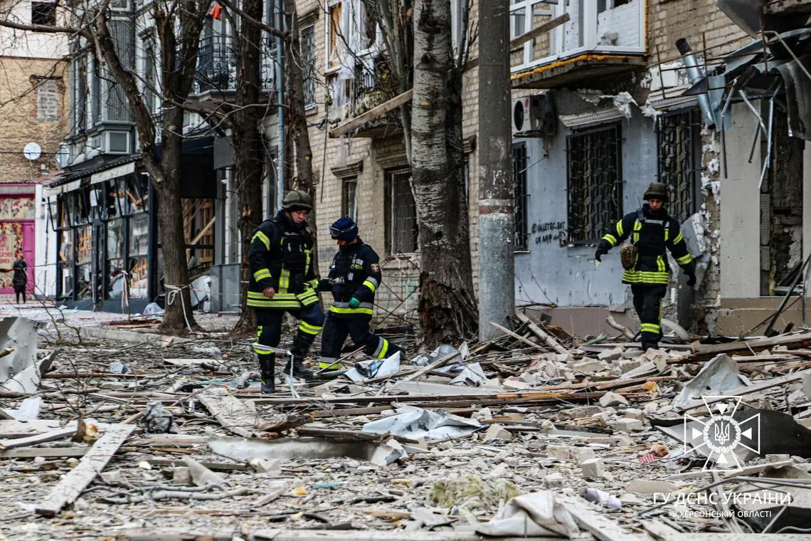 Rescuers work outside a building damaged by an air strike on the city of Kherson in Ukraine.