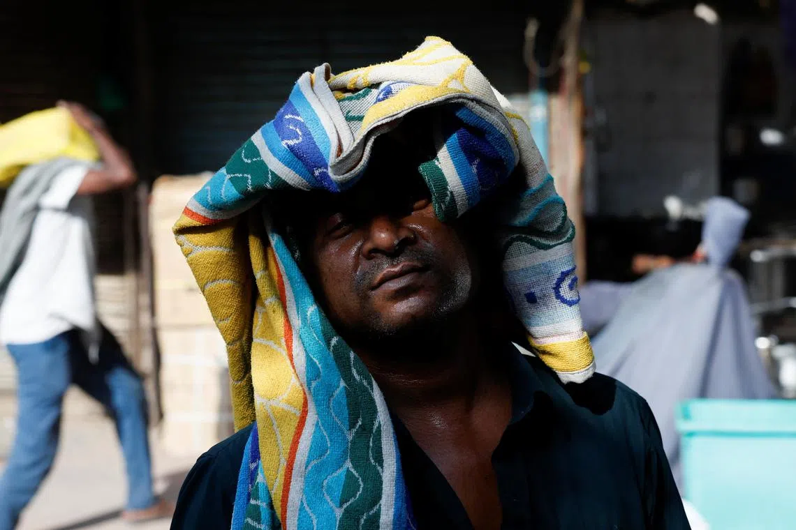A man uses a towel to protect his head from the heat on a hot summer day in New Delhi, India, May 28, 2024. REUTERS/Priyanshu Singh