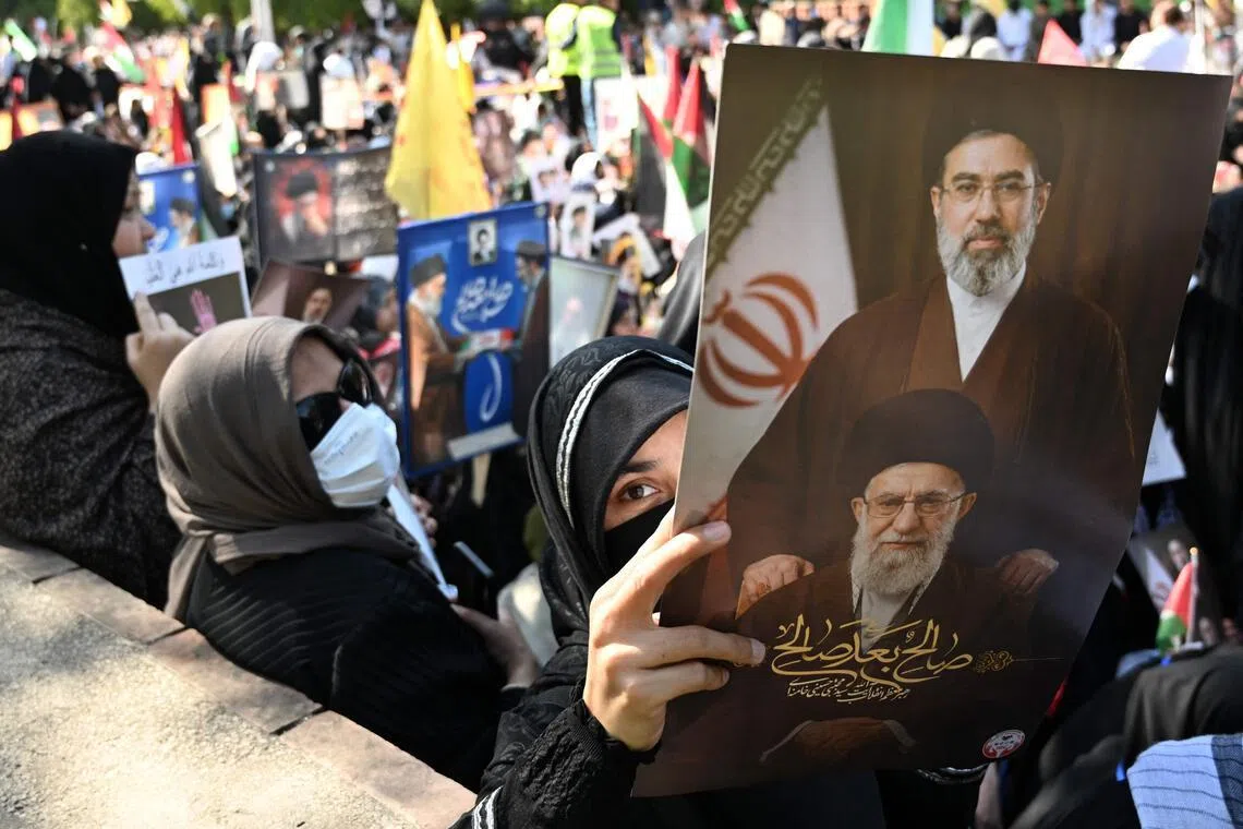 A Pakistani Shi’ite Muslim woman holding a portrait of Iran’s slain supreme leader Ali Khamenei with his son and new supreme leader Ayatollah Mojtaba Khamenei during a rally.