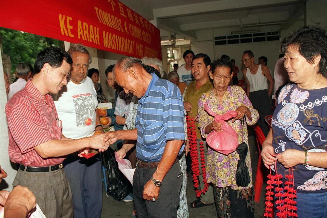 Workers' Party MP Low Thia Khiang (left) and party secretary-general J.B. Jeyaretnam (next to him) distributing hongbao and food hampers to poor, elderly residents in Hougang.