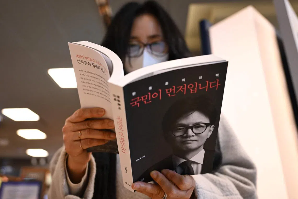 A woman reads a copy of the memoir by former leader of ruling People Power Party Han Dong-hoon, titled "The People First", at a bookstore in Seoul on February 26, 2025. South Korea's suspended President Yoon Suk Yeol would frequently "rant" about declaring martial law over drinks with colleagues, according to a new book by the former leader of his ruling party released on February 26. (Photo by Jung Yeon-je / AFP)