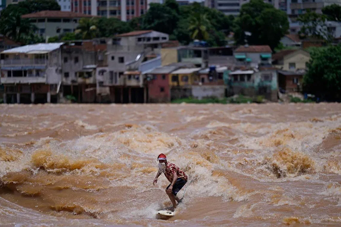 Brazilian surfer Paulo Guido surfs the Doce River while wearing a Christmas outfit in Governador Valadares, Minas Gerais state, Brazil, Dec 10, 2022. 