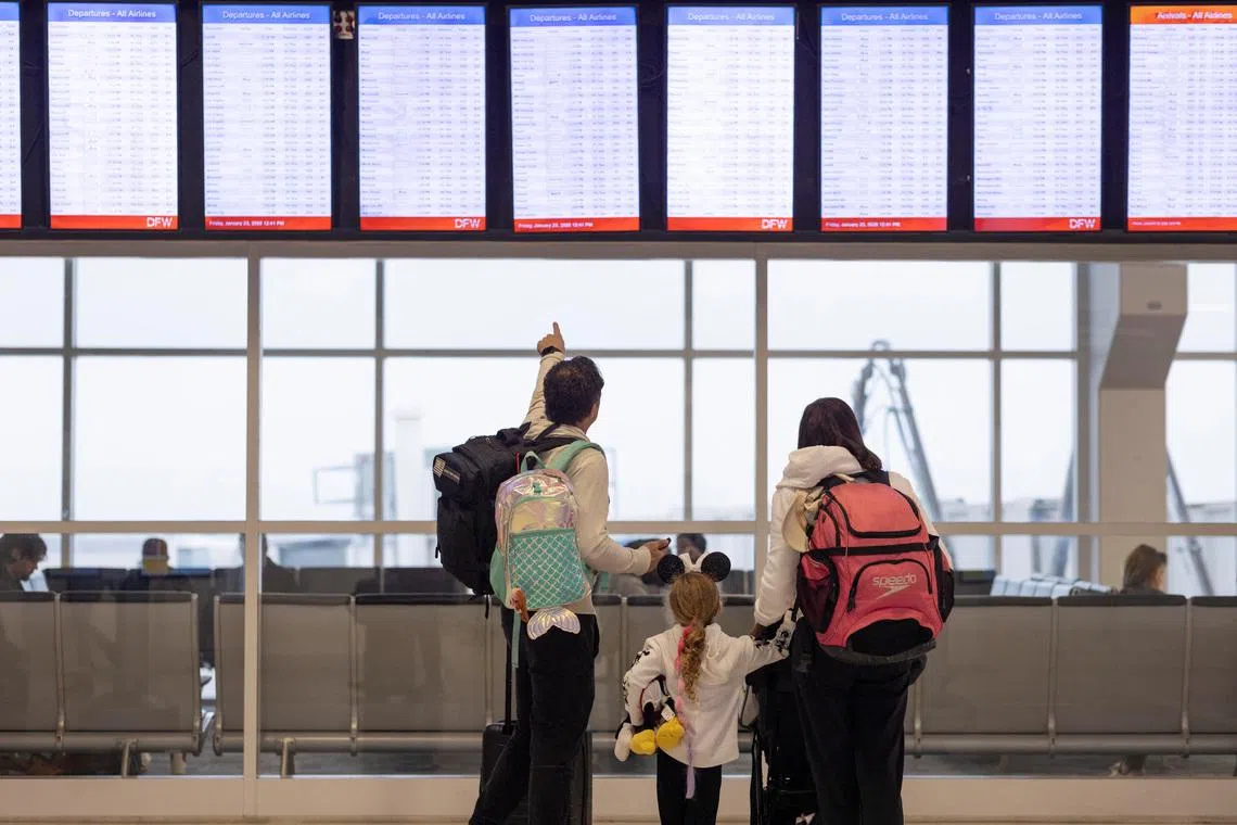 People check the flight tracker screens at the Dallas Fort Worth International Airport in Fort Worth, Texas, U.S., January 23, 2026.  REUTERS/Alyssa Pointer