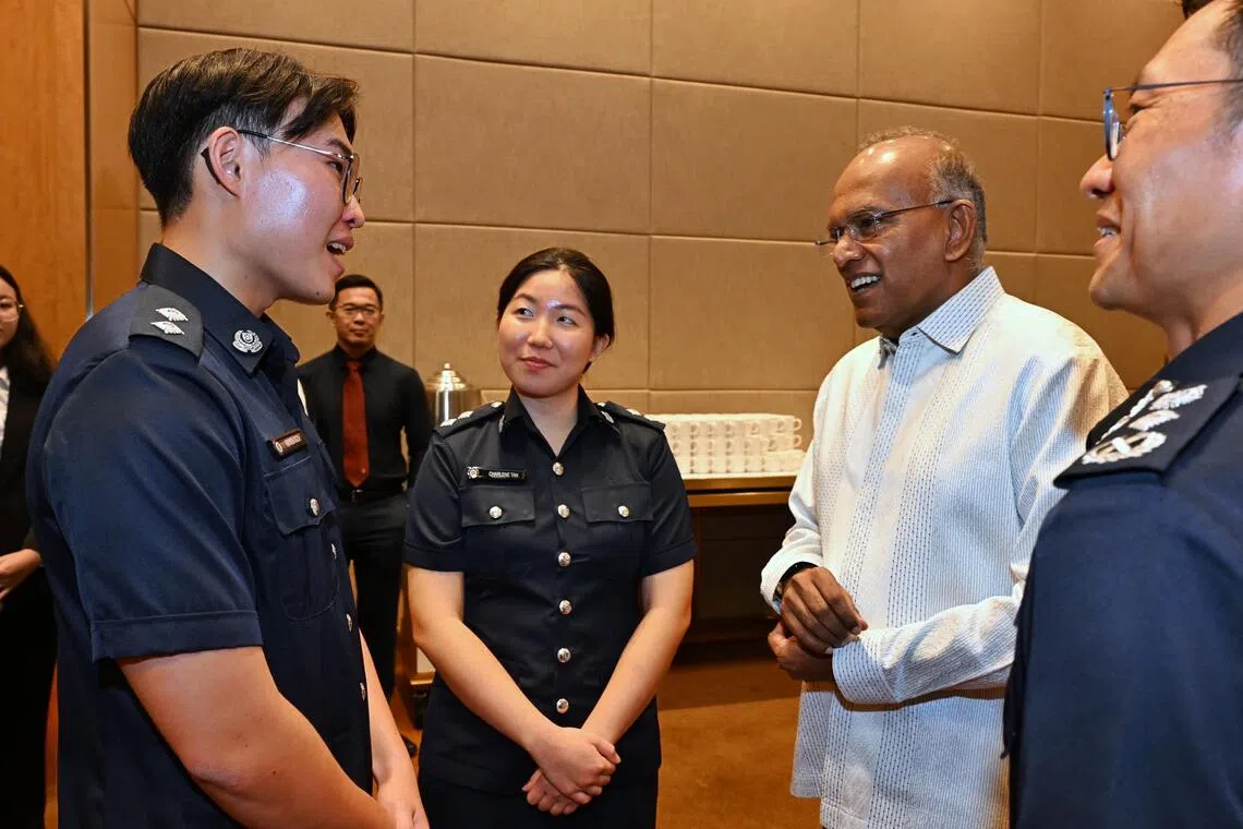Senior Minister and Coordinating Minister for National Security K. Shanmugam (2nd from right) and Commissioner of Police How Kwang Hwee (right) speaking to SPF scholarship recipients Charlene Tan and Raynen Ngoh on Aug 18.