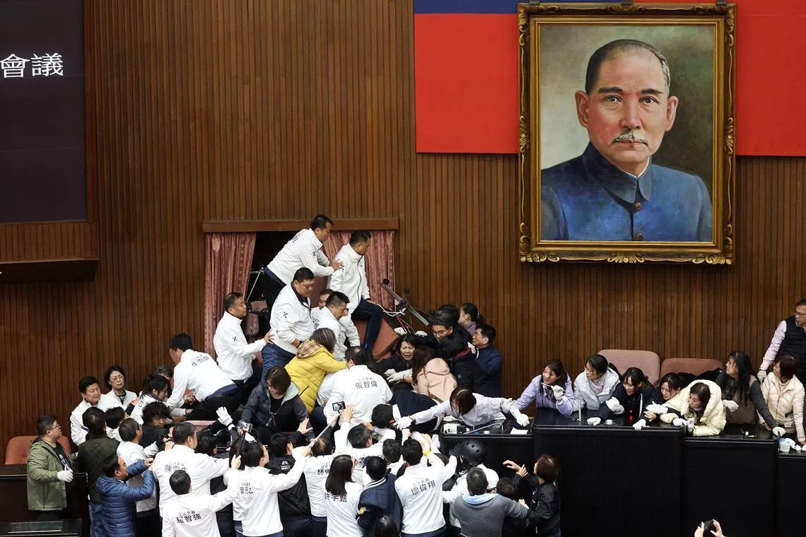 Lawmakers from the main opposition Kuomintang (KMT) (in white) try to break into Parliament where Democratic Progressive Party (DPP) occupied the night to avoid the passing of the third reading of amendments to the Civil Servants Election and Recall Act and other controversial bills at the Legislative Yuan in Taipei on December 20, 2024. (Photo by I-HWA CHENG / AFP)
