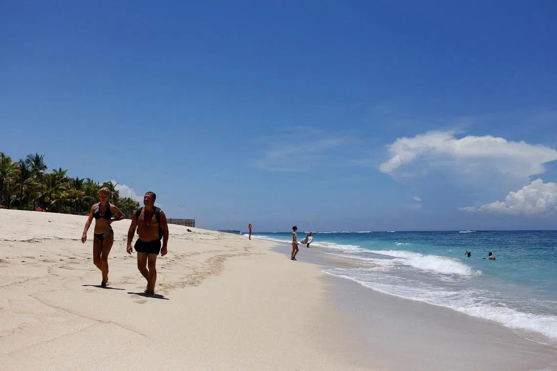 FILE PHOTO: Tourists walk along a beach in the luxury resort area of Nusa Dua ahead of Saudi Arabia's King Salman's visit on the island of Bali, Indonesia February 28, 2017. Picture taken February 28, 2017.REUTERS/Nyimas Laula/File Photo/File Photo