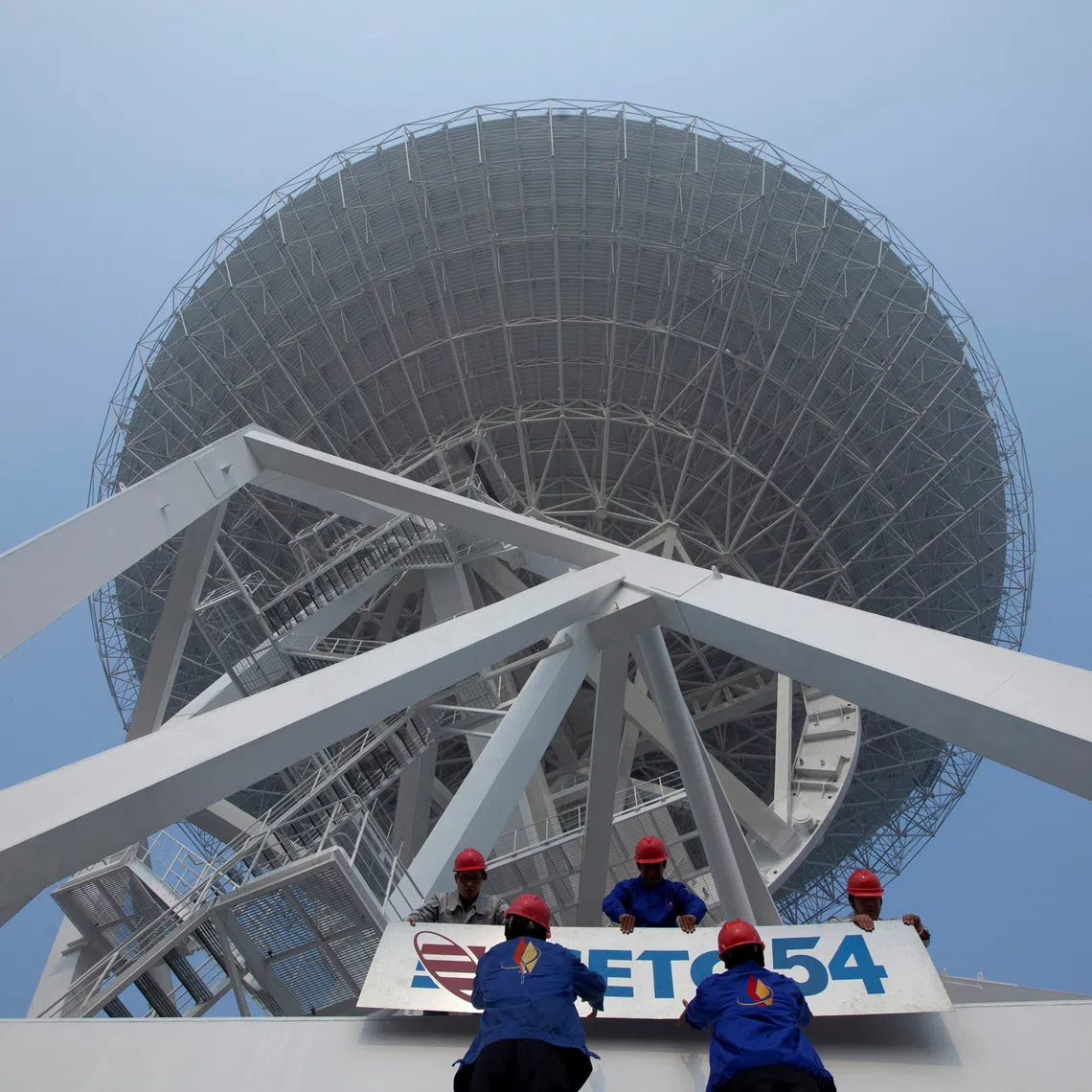 FILE PHOTO: Employees install a signage of the 54th Research Institute of CETC (China Electronic Technology Group Corporation), which takes the main responsibility of the research and development tasks of a massive radio telescope, at the foot of the telescope in Shanghai October 28, 2012. The telescope for use in space observation and was unveiled Sunday at the foot of Sheshan Mountain in Shanghai, Xinhua News Agency reported. The telescope stands at more than 70 metres (230 ft) and weighs 2,650 tonnes, according to local media. Picture taken October 28, 2012. REUTERS/Stringer (CHINA - Tags: SOCIETY SCIENCE TECHNOLOGY) CHINA OUT. NO COMMERCIAL OR EDITORIAL SALES IN CHINA/File Photo