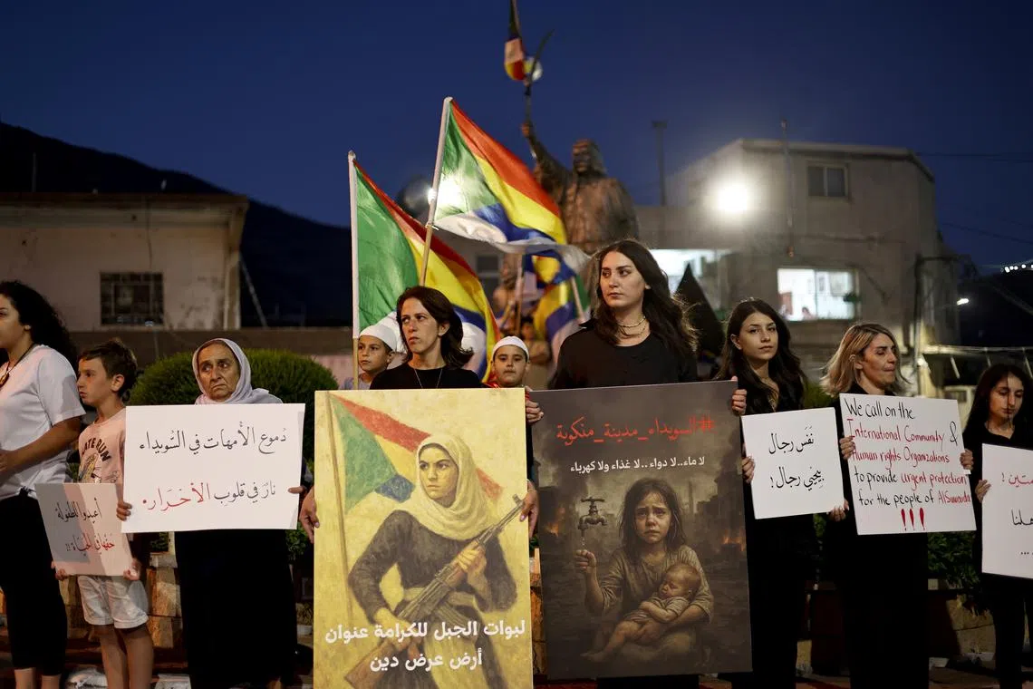 Druze activists from the village of Majdal Shams, in the Israeli-annexed Golan Heights, holding banners during a rally in solidarity with Sweida, on July 19.