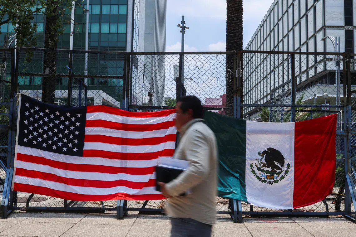 A person passes by Mexican and U.S flags placed outside the U.S. Embassy in Mexico City, Mexico June 9, 2025. REUTERS/Raquel Cunha