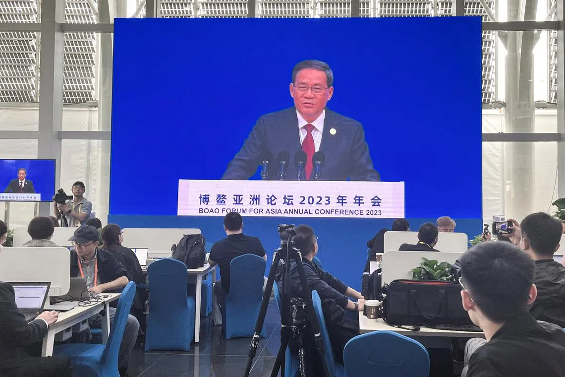 Journalists watch a giant screen broadcasting live-streaming footage of Chinese Premier Li Qiang delivering a speech at the opening ceremony of the Boao Forum for Asia Annual Conference 2023, at the media centre in Boao, Hainan on March 30, 2023..