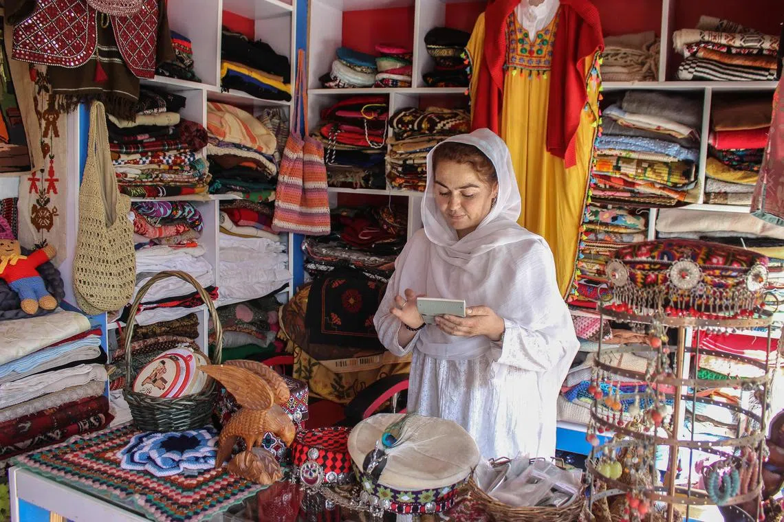 In this photograph taken on May 20, 2025, a woman shopkeeper selling traditional handmade items works at her shop in Karimabad, in the Hunza district of Pakistan's Gilgit-Baltistan region. In a sawdust-filled workshop nestled in the Karakoram Mountains, a team of women carpenters chisel away at cabinets -- and forge an unlikely career for themselves in Pakistan. Women make up just a fraction of Pakistan's formal workforce. But in a collection of villages sprinkled along the old Silk Road between China and Afghanistan, a group of women-led businesses are defying expectations. (Photo by Manzoor BALTI / AFP) / To go with 'Pakistan-Women-Economy-Hunza', REPORTAGE by Nisar ALI