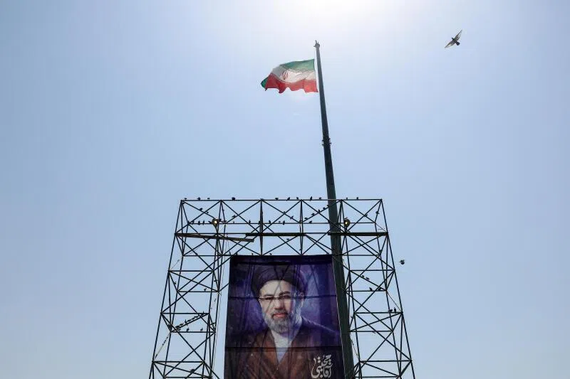 An Iranian flag flying above a poster of Iran’s Supreme Leader Mojtaba Khamenei, in Tehran. Observers say the Trump administration faces an uphill battle to permanently lift Iran sanctions.