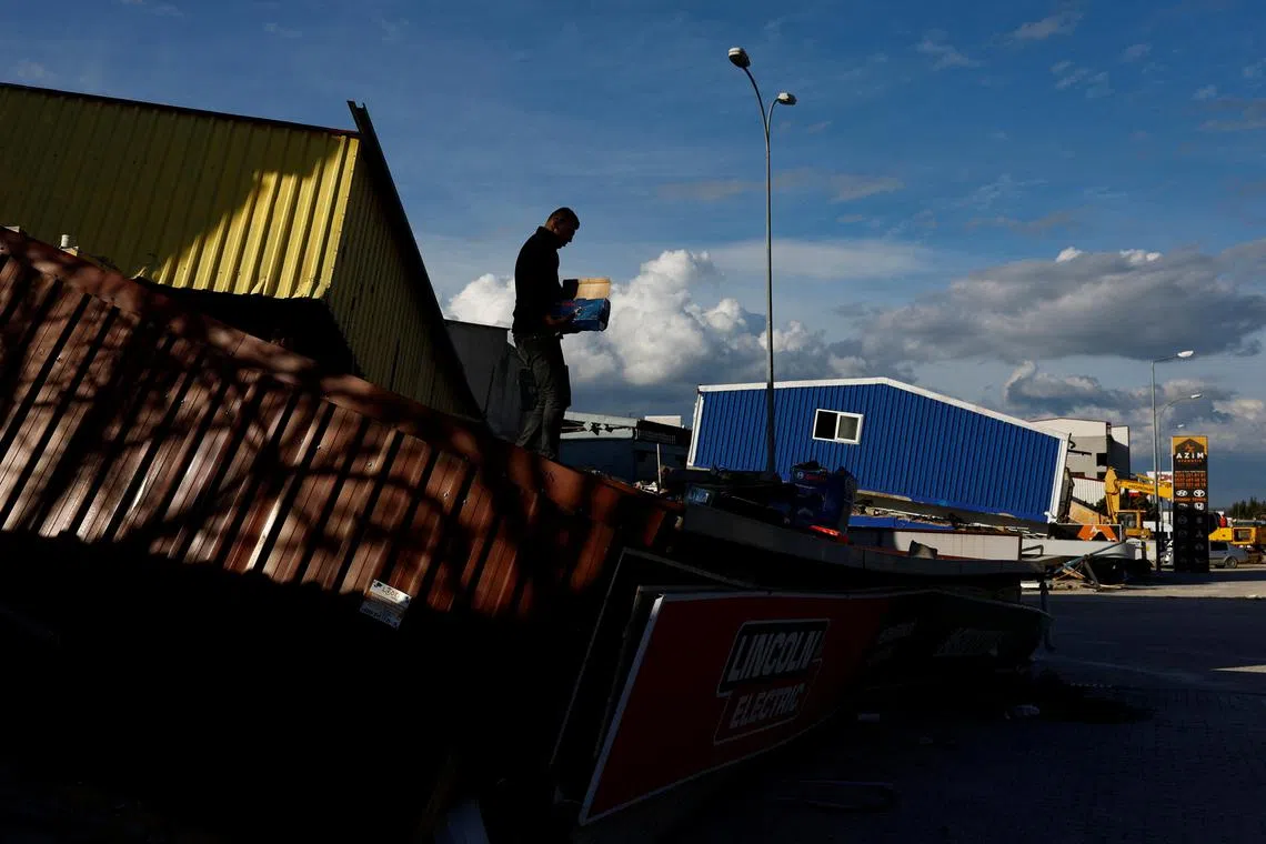 A worker salvages items from an electric store in Antakya Kucuk Sanyi Sitesi Industrial Estate, in the aftermath of the deadly earthquake in Antakya, Hatay province, March 7, 2023. REUTERS/Susana Vera
