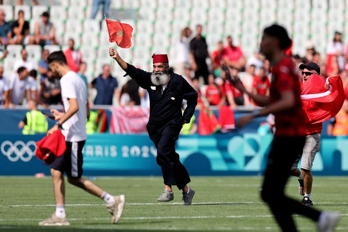 Paris 2024 Olympics - Football - Men's Group B - Argentina vs Morocco - Geoffroy-Guichard Stadium, Saint-Etienne, France - July 24, 2024. Pitch invaders are seen on the pitch at the end of the match before is suspended. REUTERS/Thaier Al-Sudani     TPX IMAGES OF THE DAY