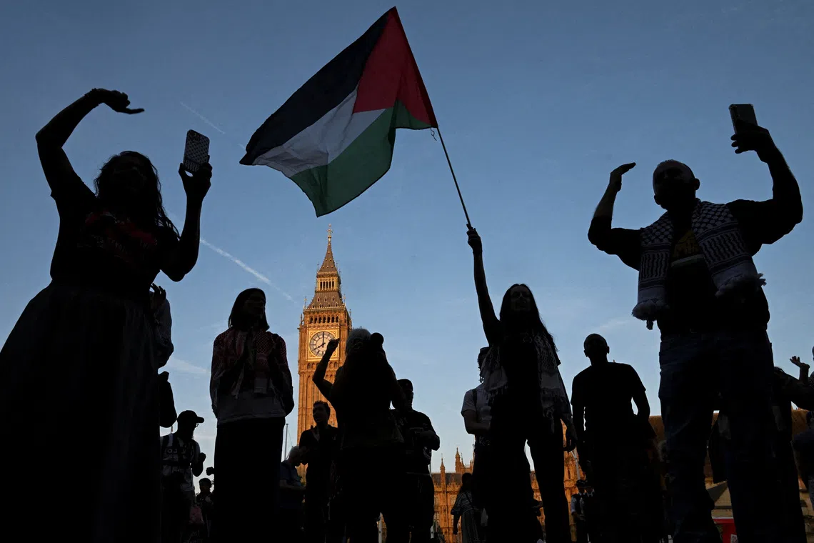 FILE PHOTO: A woman holds a Palestinian flag as demonstrators attend a rally organised by Defend Our Juries, challenging the British government's proscription of \"Palestine Action\" under anti-terrorism laws, in Parliament Square, in London, Britain, August 9, 2025. REUTERS/Jaimi Joy/ File Photo