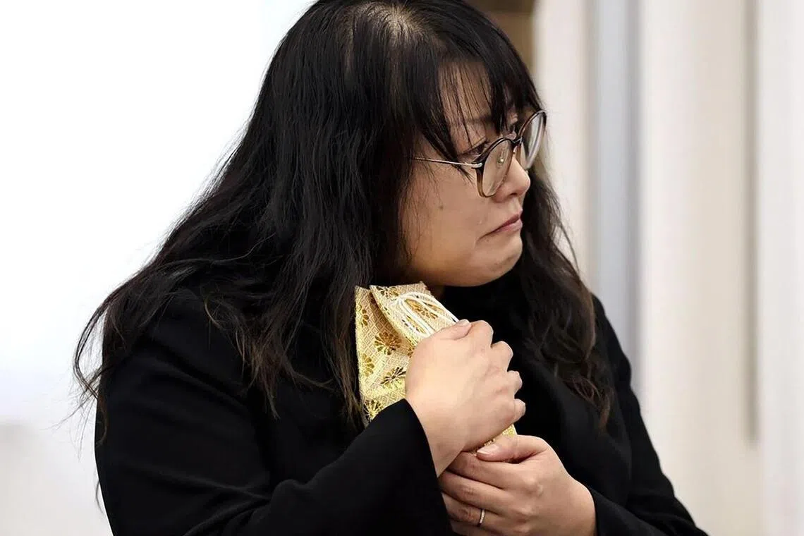 Ms Chiyumi Yamane cuddling the small urn containing the partial remains of her daughter Natsuse.