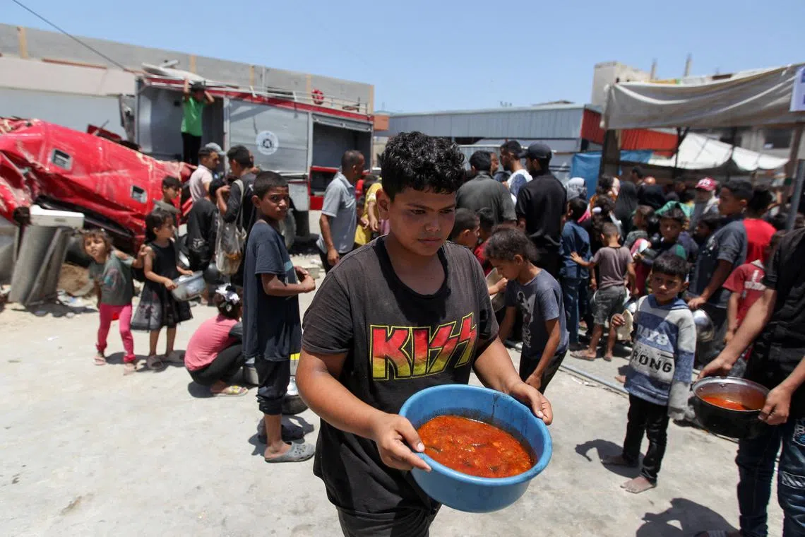 FILE PHOTO: A Palestinian carries food cooked by a charity kitchen, amid shortages of aid supplies, as the conflict between Israel and Hamas continues, in Khan Younis, in the southern Gaza Strip, June 19, 2024. REUTERS/Hatem Khaled/File Photo