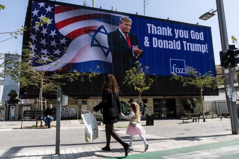 People walk by a billboard commissioned by an evangelical group, which displays a picture of US President Donald Trump, in Tel Aviv, Israel, on March 12.