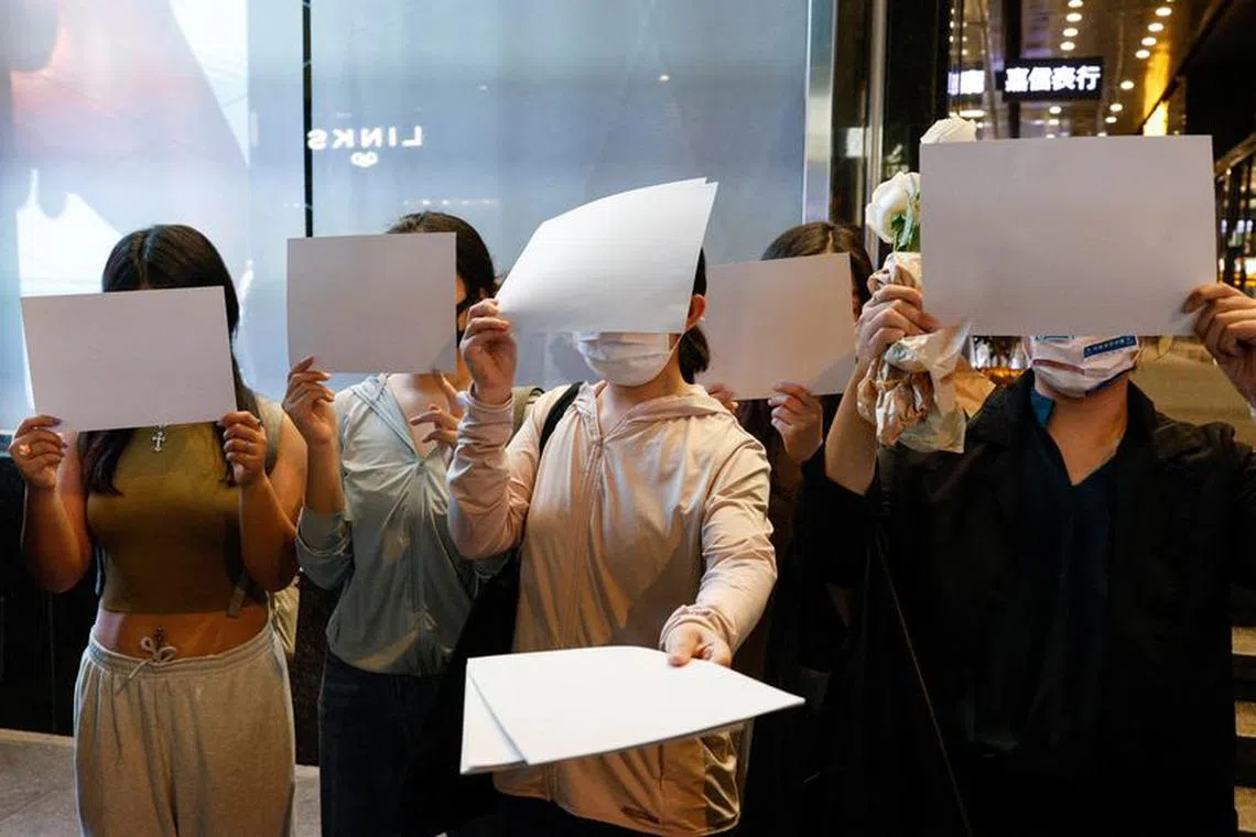 People hold white sheets of paper in protest over coronavirus disease (COVID-19) restrictions in mainland China, during a commemoration of the victims of a fire in Urumqi, in Hong Kong, China November 28, 2022. REUTERS/Tyrone Siu/File Photo