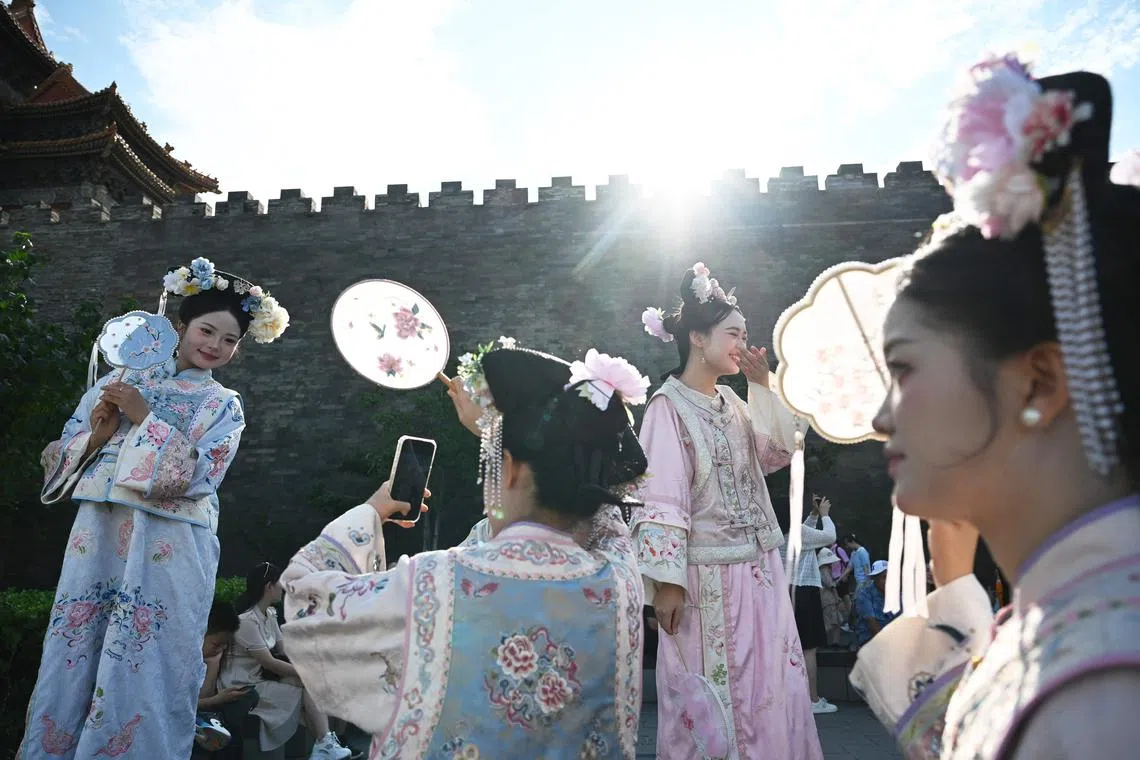 Women dressed in imperial-style costumes posing for photos outside the Forbidden City in Beijing, on July 20, 2025. 