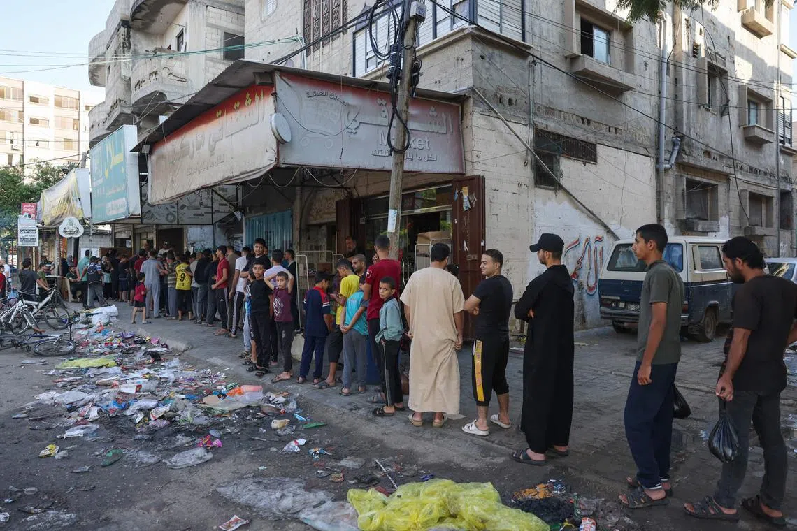 Palestinians queue to buy bread from a bakery in Rafah in the southern Gaza Strip on Oct 18, 2023. 